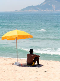 Мужчина на пляже под зонтом