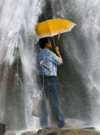 Мужчина с зонтом под водопадом